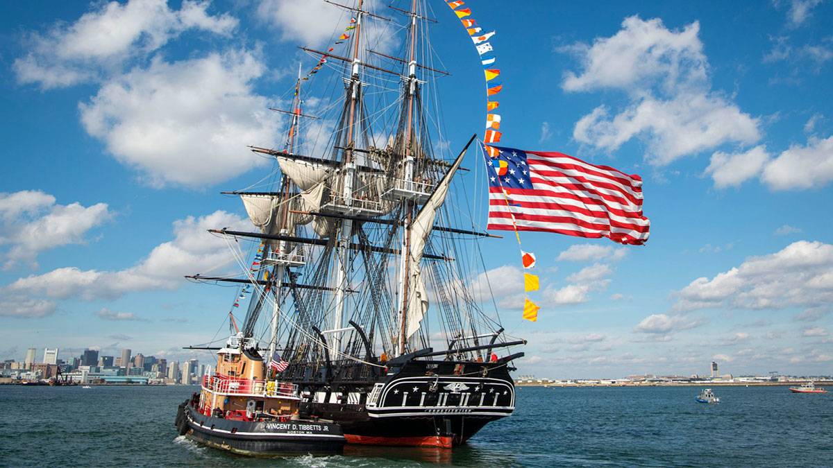 boat with american flag on water during day with blue sky and clouds for USS Constitution Turnaround Boston 4th of July in Boston, Massachusettes, USA